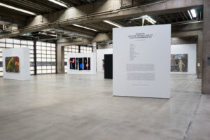 This photo shows the entrance of the Great Hall, where we see the architecture of the building and large, white walls with artwork hung on them.